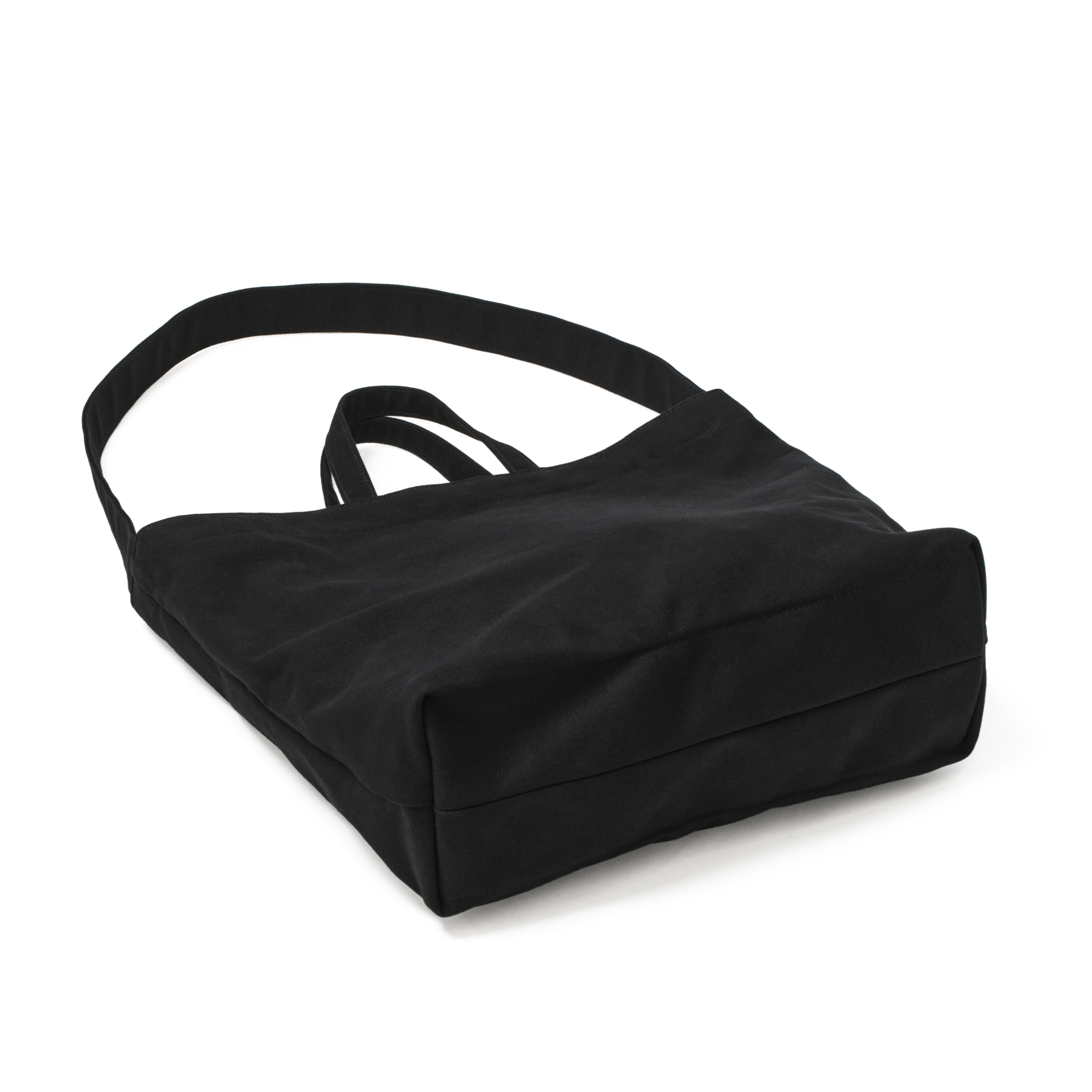 Angled back view of the MAKR Vert Sling Tote in Black heavy cotton duck canvas.